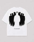 Achterkant van het witte BE YOURSELF T-shirt van FAKESNIFF, met een zwart geschilderde menigte met in het midden een lege, witte figuur, met de tekst 'be yourself.'
