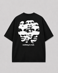 Achterkant van het zwarte NOTHING IS REAL T-shirt van FAKESNIFF, met een wit vervormd gezicht in horizontale banen, met de tekst 'nothing is real.'