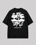Achterkant van het zwarte NOTHING IS REAL T-shirt van FAKESNIFF, met een wit vervormd gezicht in horizontale banen, met de tekst 'nothing is real.'