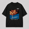 Zwart oversized HIGH ON THIN AIR T-shirt van FAKESNIFF, print 'high on thin air': een vrouw snuift door een opgerold bankbiljet boven de condensstreep van een vliegtuig