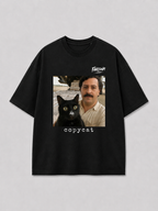 Zwart oversized PABLO T-shirt van FAKESNIFF, print 'copycat': een zwarte kat naast een man met snor voor gestapelde koffiezakken