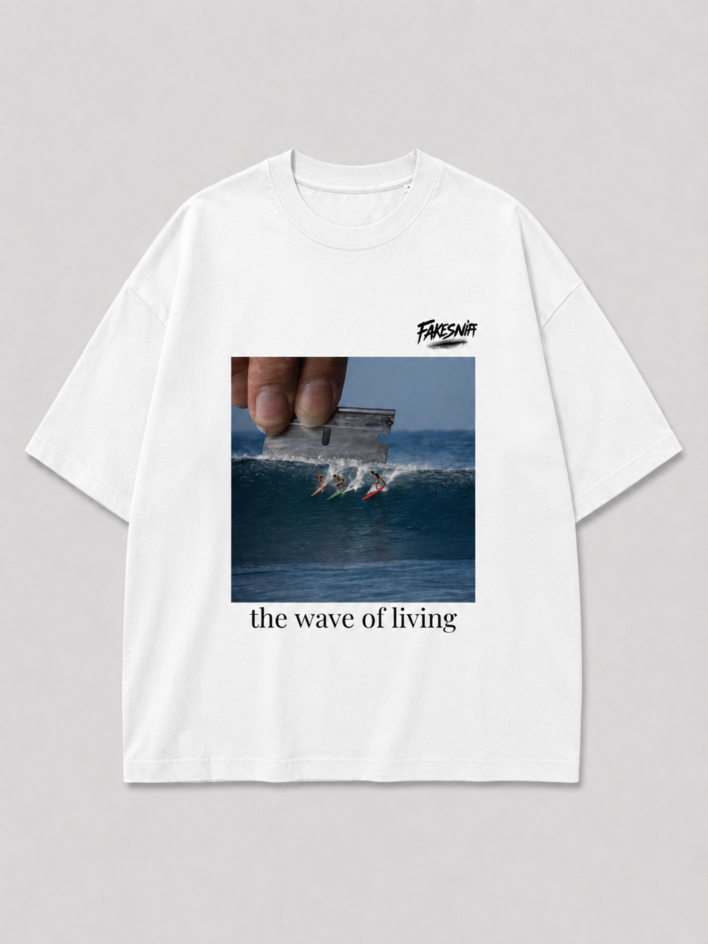Wit oversized THE WAVE OF LIVING T-shirt van FAKESNIFF, print 'the wave of living': een hand houdt een scheermesje boven een golf waarop drie surfers rijden